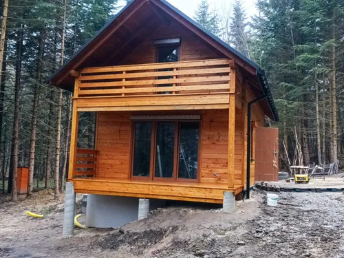 Dom drewniany z balkonem z poziomych desek, otoczony lasem