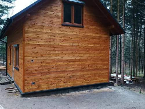 Dom szkieletowy z drewnianą elewacją i blaszanym dachem w lesie