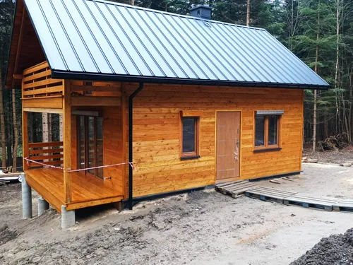 Front domu drewnianego z drzwiami wejściowymi i narożną werandą