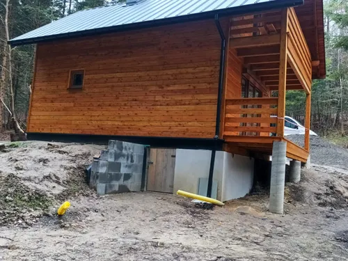 Dom drewniany z balkonem i werandą na słupach, blaszany dach
