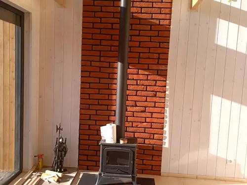Wnętrze z piecem kominkowym i ceglaną ścianą przy wysokim oknie