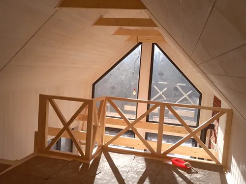 Wnętrze antresoli pod skosem dachu, drewniana balustrada, okno szczytowe