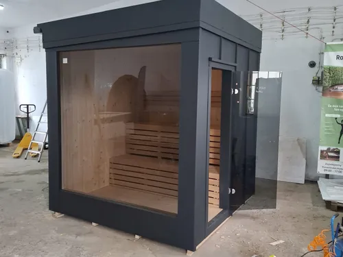 Sauna ogrodowa z przeszkloną ścianą, widoczne wnętrze z drewnianymi ławami